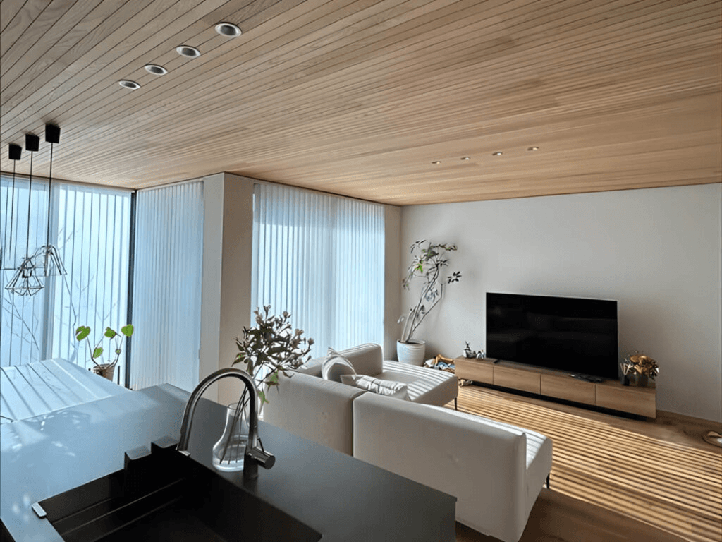 リビングの木張り天井と建て型ブラインド、床の木目のラインが美しい
